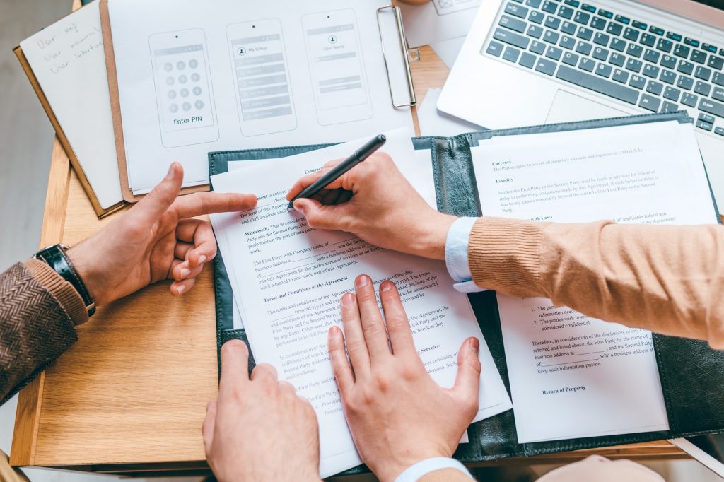 One of partners pointing at contract while his colleague putting personal data